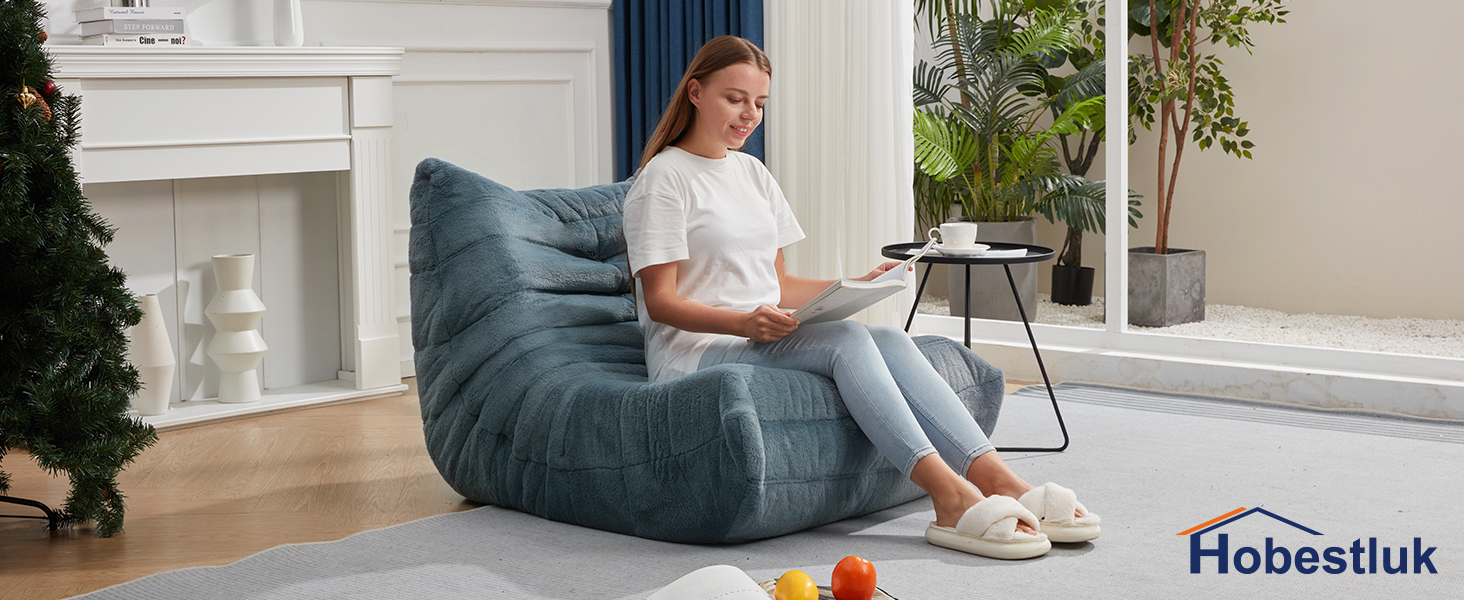 a girl lay one the large fireside sofa to read book